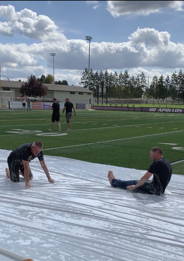 These guys are ALL IN.  Campus Monitor Erik “Chief” Chosvig and Principal John Huelskamp slip and slide in front of Sunset’s students at Friday’s outdoor pep assembly.