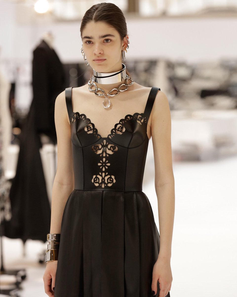 A black corset dress with a deep knife pleat skirt is edged with
