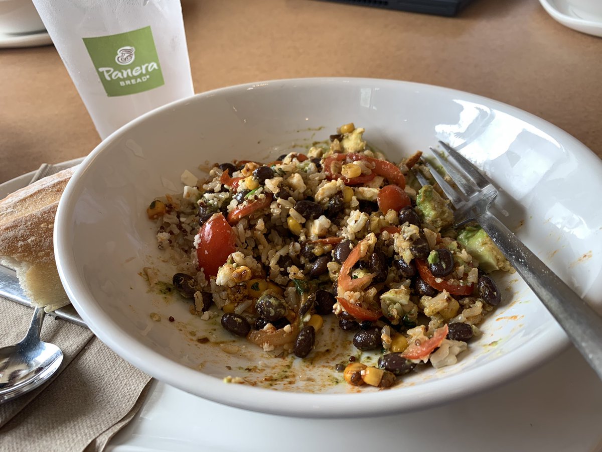 A Baja Bowl on a table with a fork in it and a Panera drink cup beside it.