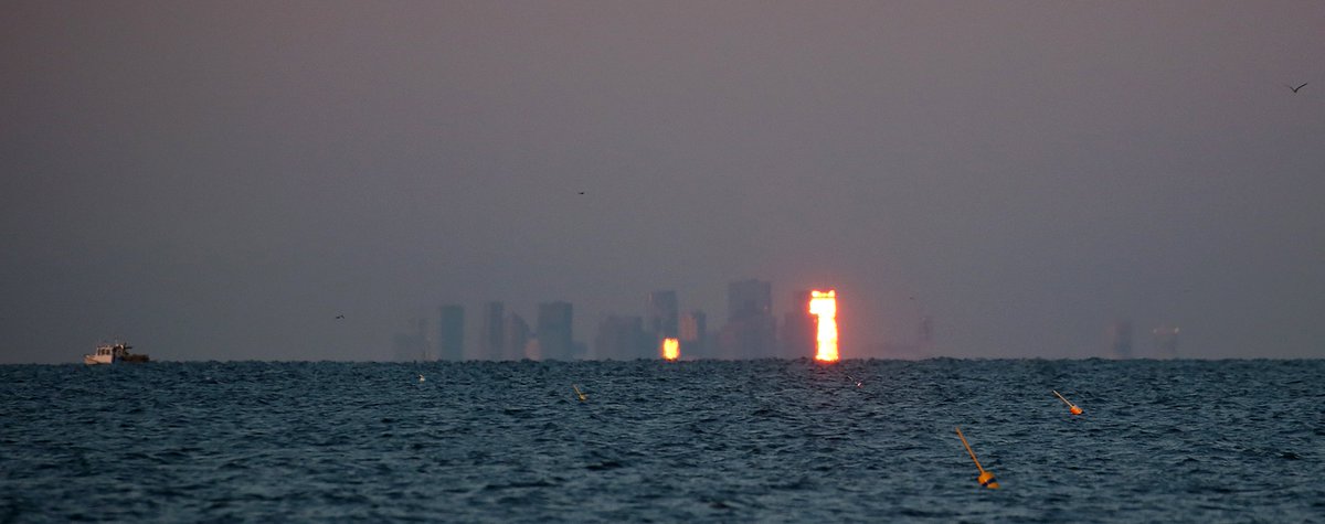 REFLECTIONS... At sunrise off the coast of Gloucester as the day starts off the city of Boston reflects the sun on some of it's skyscrapers.
