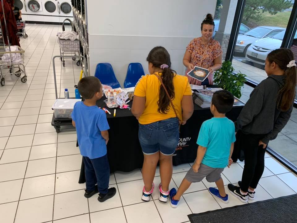 LoudounLibrary's tweet photo. Wash, dry, fold -- and sign up for a library card! 👕📚 #SterlingLibrary staff visited our local laundromat this week to spread the word about all the wonders that the library has to offer. If you don't have a library card, you can register online at https://t.co/9ZF8wfMUmr. https://t.co/XQgNU3nSVW