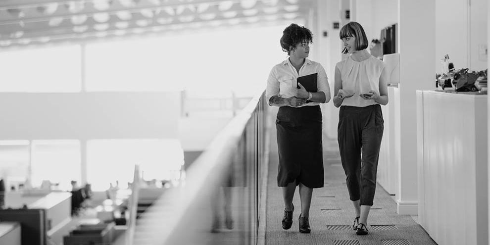 2 women walking in a workplace