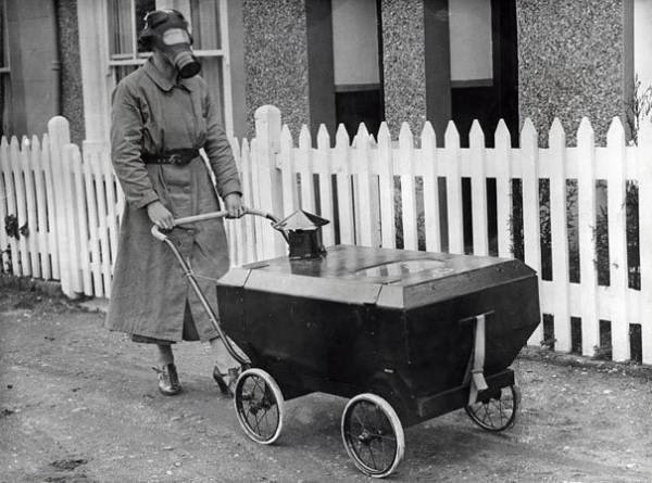 11- Se parer à une attaque au gaz :En 1938 en Angleterre, une femme porte un masque à gaz et pousse un berceau équipé lui aussi pour parer une éventuelle attaque au gaz