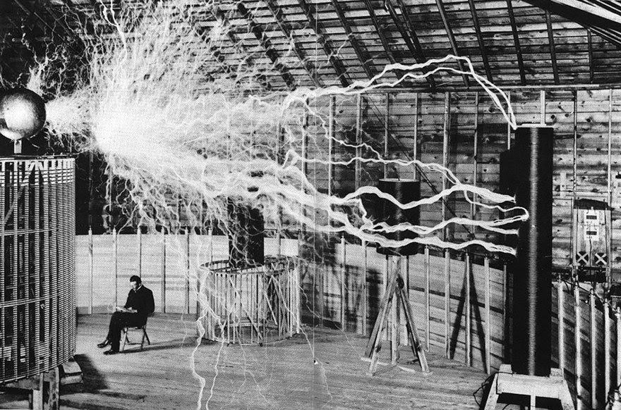 38- L’ingénieur et physicien Nikola Tesla, tranquillement assis pendant une expérience de l’une de ses inventions, un gigantesque résonateur électrique à haute fréquence.