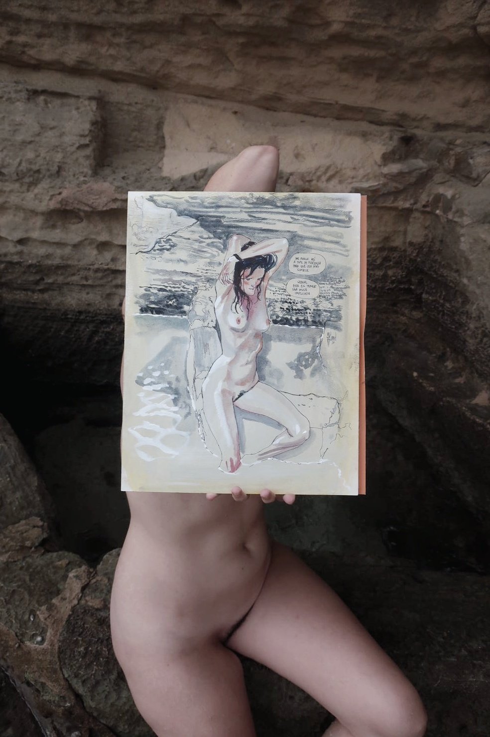Foto d'un dibuix fet al natural a la platja amb la model despullada, que el té damunt tapant-li el cos