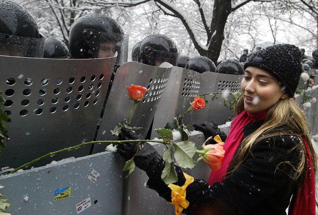 73- Lors de la révolution Orange, une ukrainienne place des roses sur les boucliers des forces de l'ordre présentes devant le siège présidentiel à Kiev. (2004)