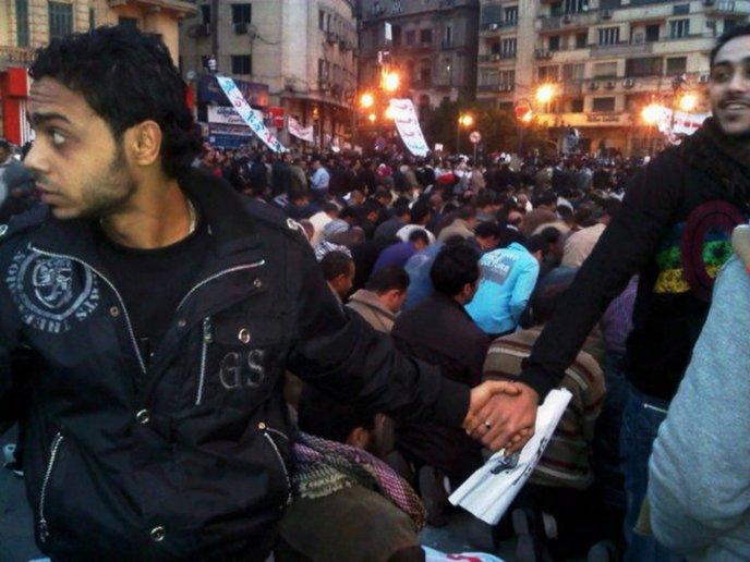 91- Un groupe de chrétiens protège les musulmans qui prient pendant les émeutes du Caire lors du printemps arabe.