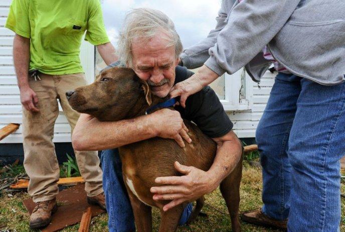 96- En Alabama, un homme enlace son chien après l'avoir retrouvé dans sa maison détruite suite au passage d'une tornade.