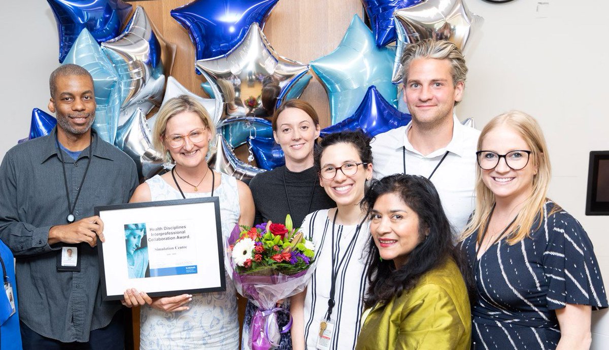 7 members from the St. Michael's Interprofessional Practice Team standing in front of balloons and holding a certificate.