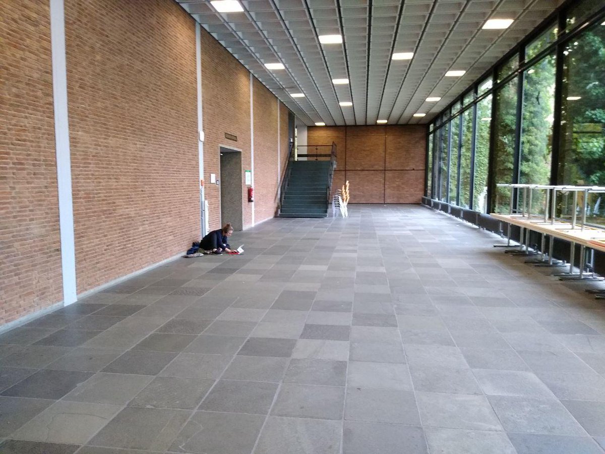empty floor of the venue, with one person sitting charging her devices