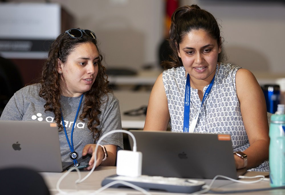 two women confer at laptops