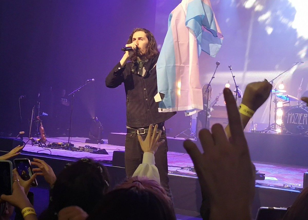 Hozier holding a trans pride flag during a show in London, he is one of the celebrity allies who came out in support during 2020