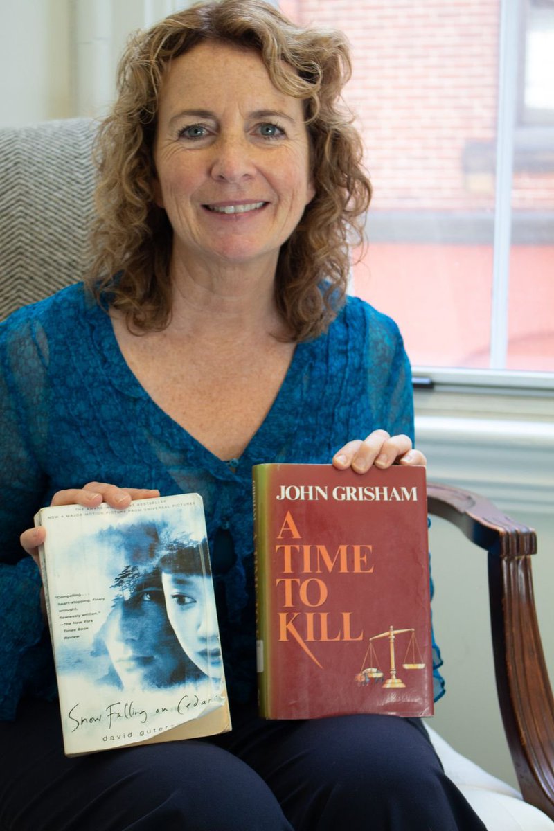 Beth Ansheles, ACLU of Maine Finance Director, holding copies of Snow Falling on Cedars by David Guterson and A Time to Kill by John Grisham