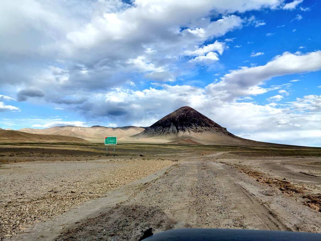 royxy's tweet image. 昨天旅途中比较魔幻风格的场景。经过一百多公里完全荒无人烟的贫瘠草原之后，在一座死火山脚下，突然出现了一块绿色的牌子。我们走近一看，是农行的“三农金融服务点”。那地方绝对是middle of nowhere ，放眼望去几十公里肯定没有人烟…农业银行这网点铺设做得也太到位了吧… #西北偏南