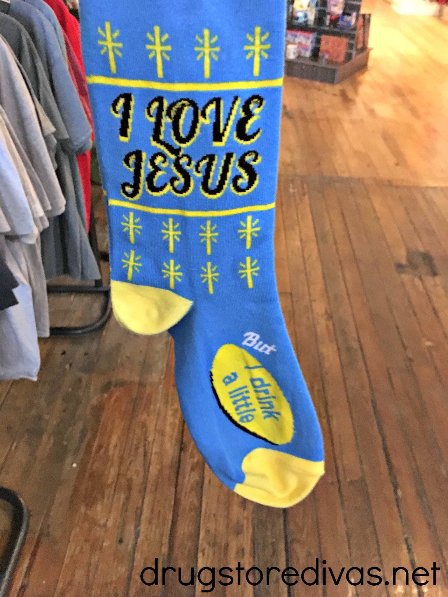 A pair of blue and yellow socks that says "I love Jesus but I drink a little."