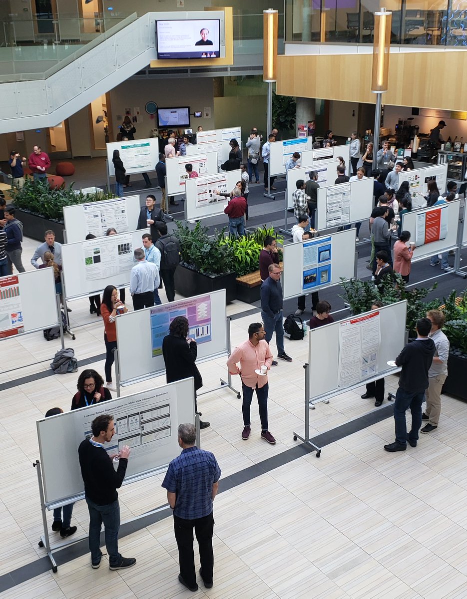 Students and guests look at poster presentation in the building lobby.