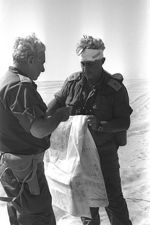 גם אריק שרון נפצע קלות, כאן בתמונה בשיחה עם המילואימניק, שר המסחר והתעשיה, מפקד חזית הדרום, רב אלוף חיים בר לב. בר לב החליף אלוף פיקוד הדרום, שמואל גונן (גורודיש) בעקבות תפקודו הכושל בימי הלחימה הראשונים.צילום: גרינברג יוסי - לע"מ