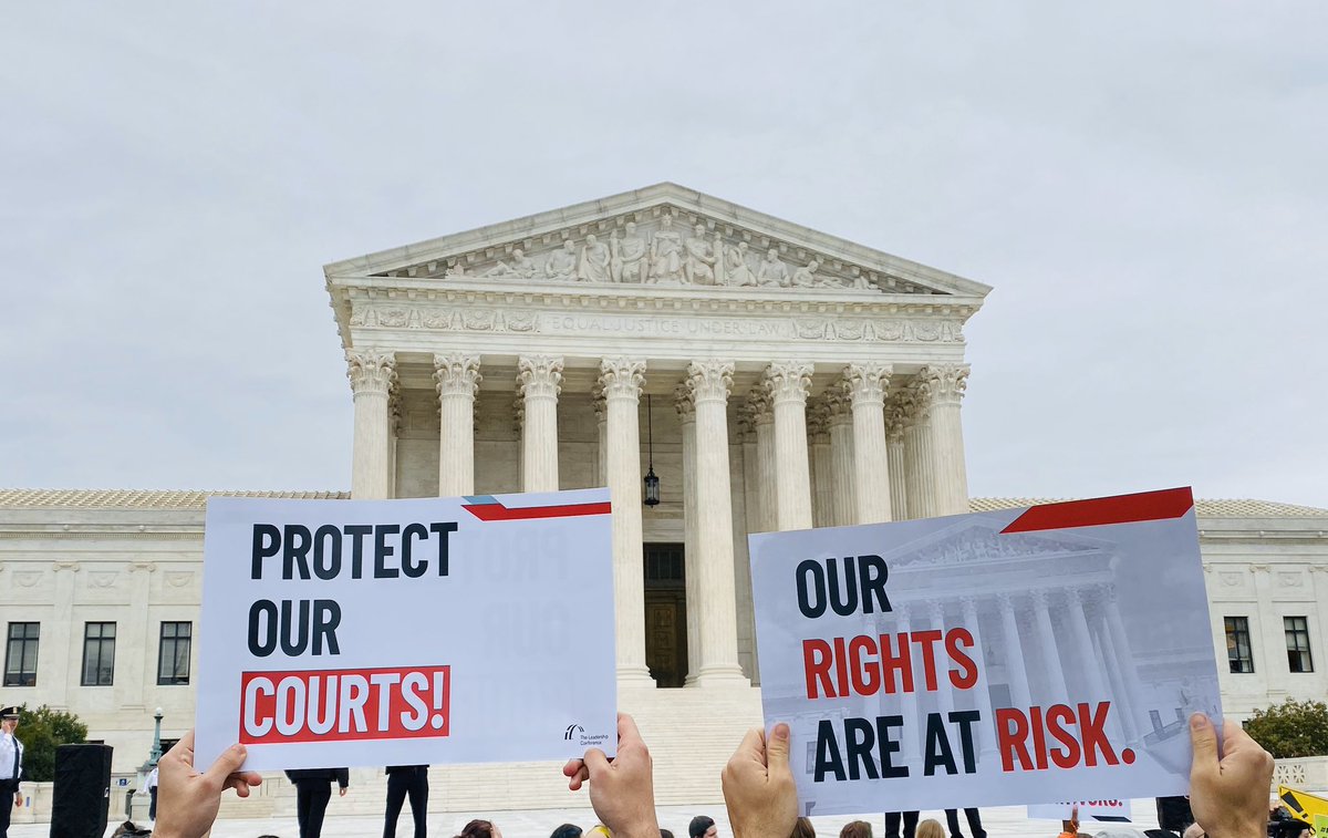 Two signs in front of the Supreme Court say “Protect Our Courts” and “Our Rights Are At Risk.”