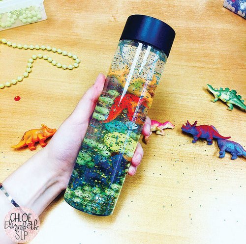 Sensory bins and bottles are powerful treatment tools—they’re so engaging and can be used to target many different goals. In this bottle, I used water, glitter, glue, beads, buttons, craft jewels, and plastic dinosaurs. #slpeeps on.asha.org/2VcdWsQ