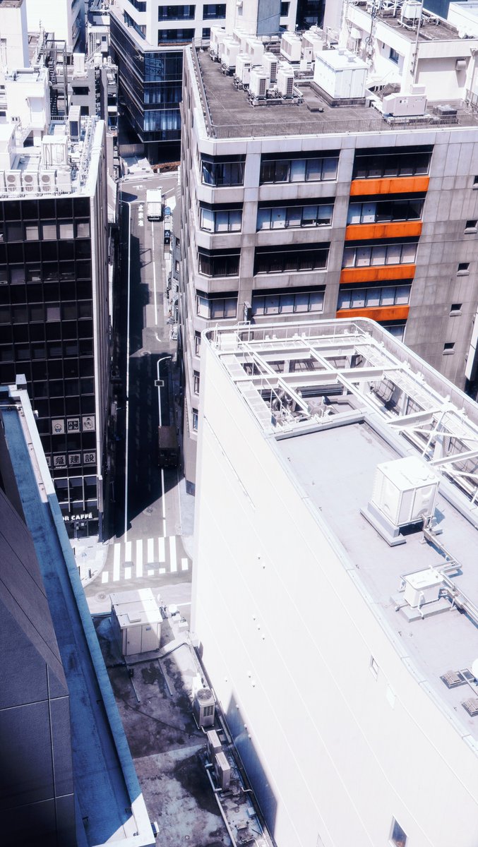 Photography by Liam Wong of Tokyo during the day. Bright white architecture, harsh shadows and cold tones are reminiscent of the city in the video game Mirror's Edge. This image is overlooking many buildings from above. Accented colors draw attention to the structures.
