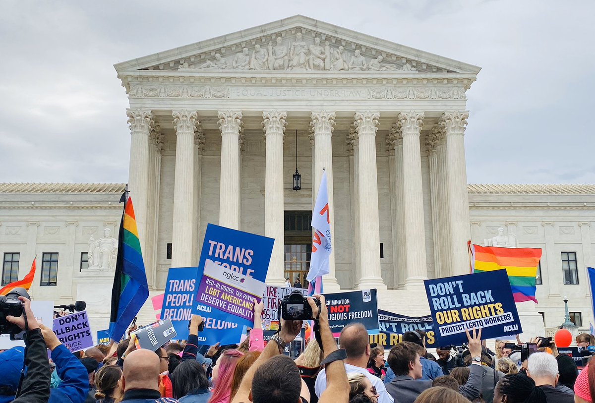 Signs in support of LGBTQ equality wave in front of the US Supreme Court as the Court hears an LGBTQ employment discrimination case.