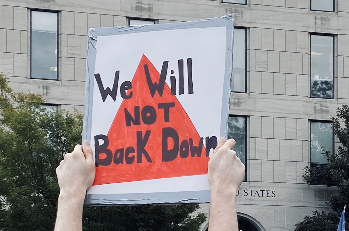 Person holds sign that reads “We will not back down.”
