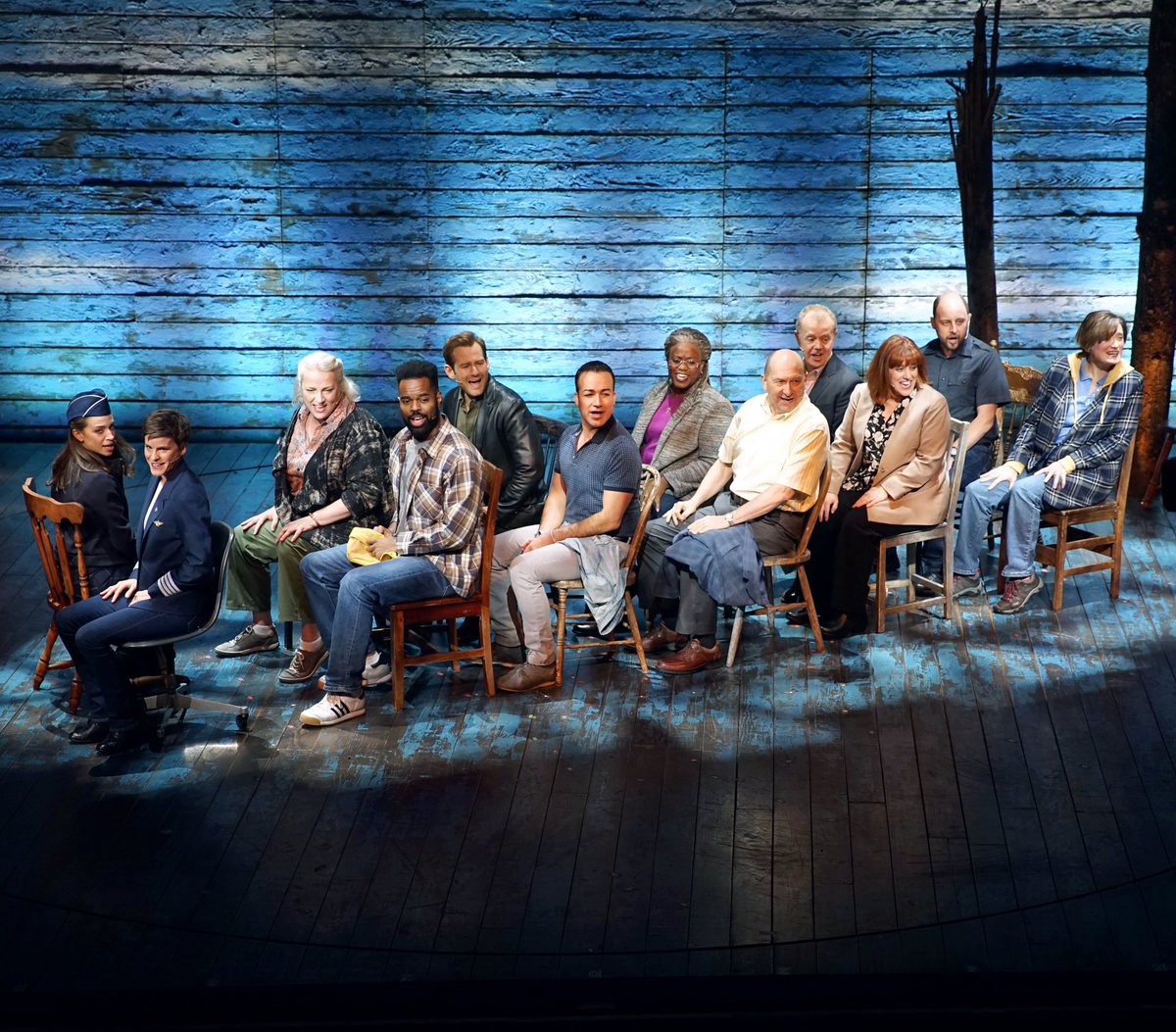 The Come From Away cast sitting in the set plane on stage at the Schoenfeld Theatre.