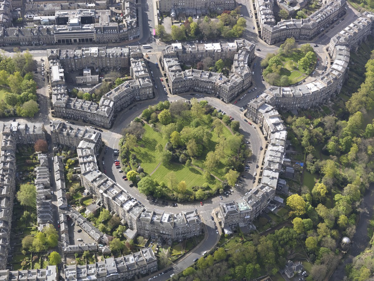 A green-space roundabout surrounded by tenement buildings and trees.