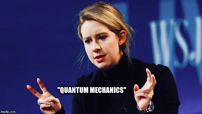 Elizabeth Homes doing air quotes for the word "quantum mechanics"