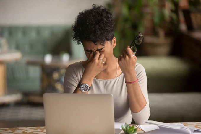 Woman sitting at computer rubbing eyes