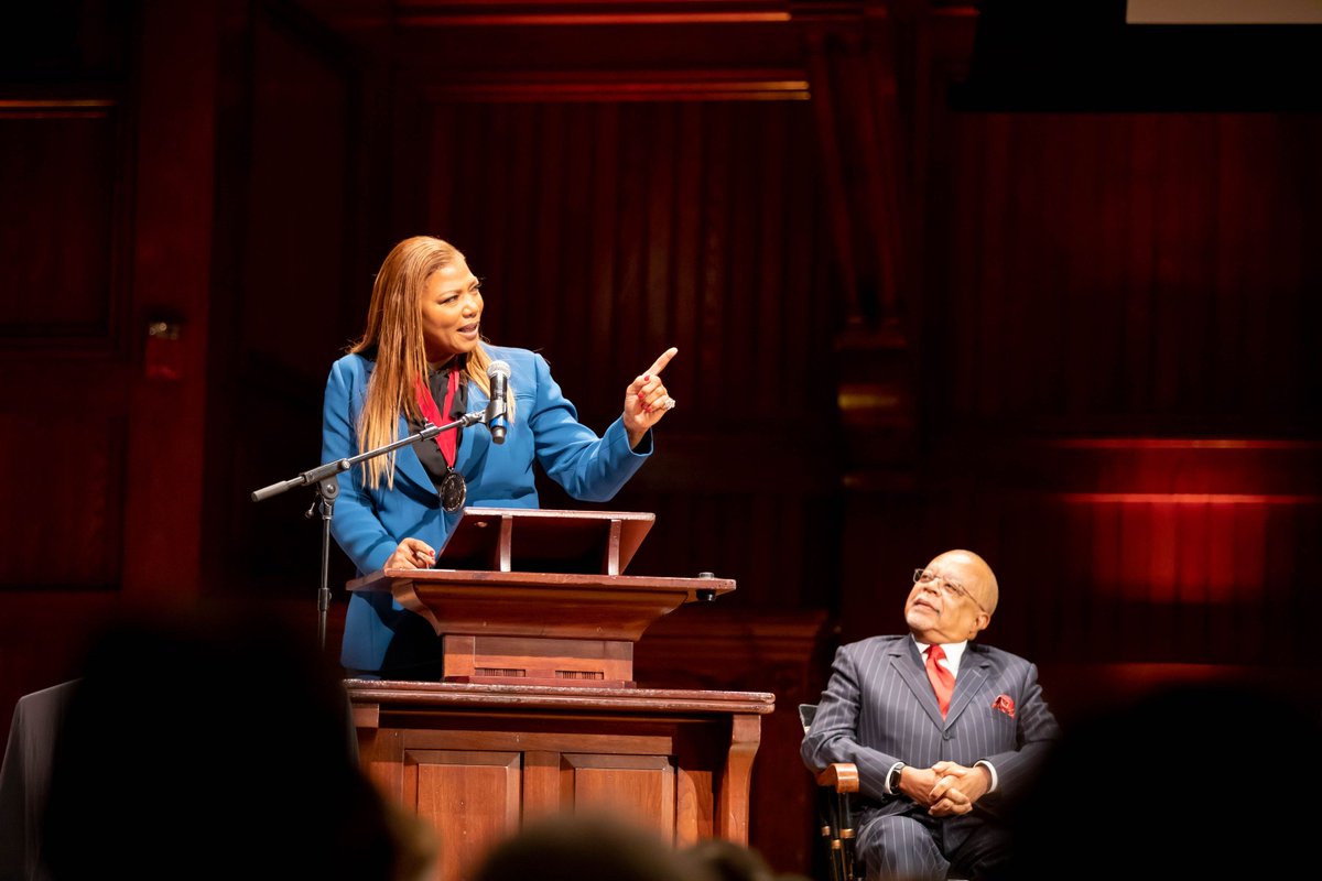 Queen Latifah at the podium while Henry Louis Gates, Jr. looks on
