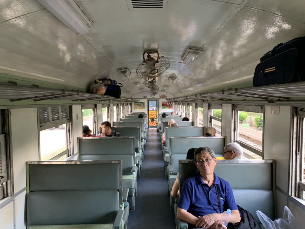 My coach at the moment. Quite empty. The heat has sucked energy off the inhabitants. My coach is next to the locomotive (SRT written in yellow in front) that is very noisy when it cranks up. The windows and doors are all open. One can go touch the locomotive as well. &ndash; bei  สถานีรถไฟโพรงมะเดื่อ (Phrong Maduea) SRT4018