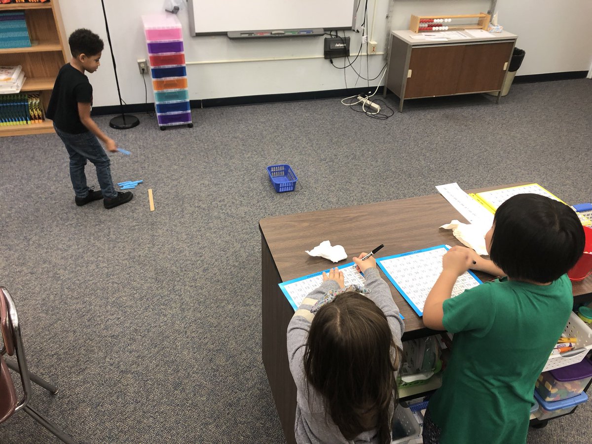 2nd graders practice counting by 10s as they toss 10s rods in a bucket. The scorekeepers highlight the 10s on the 100s chart. Crazy fun in math today. The next round we tossed dimes. #wds1920 #gcpride