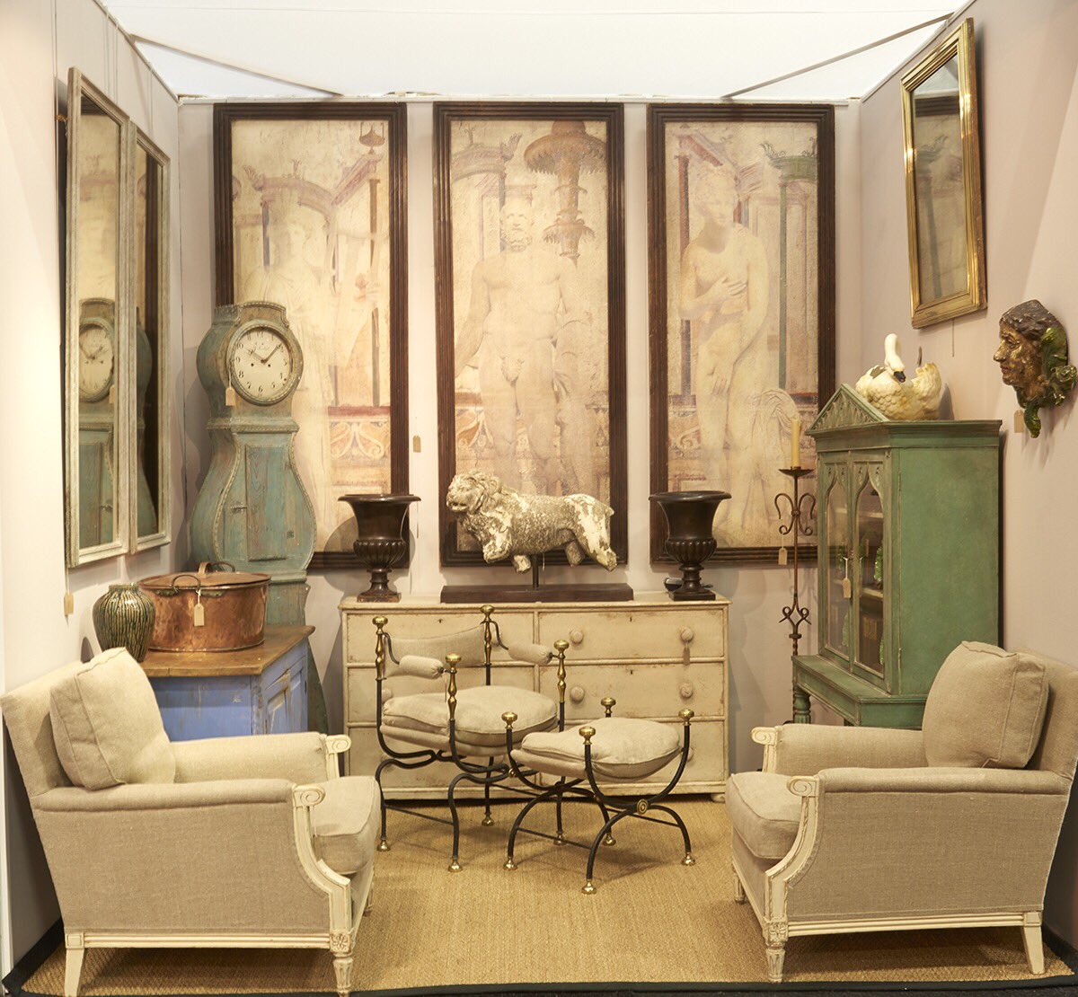 A Swedish clock looks perfectly at home alongside some wall panels depicting Roman figures, @marchand_antiques balances time, place and tone perfectly. #decorativefair