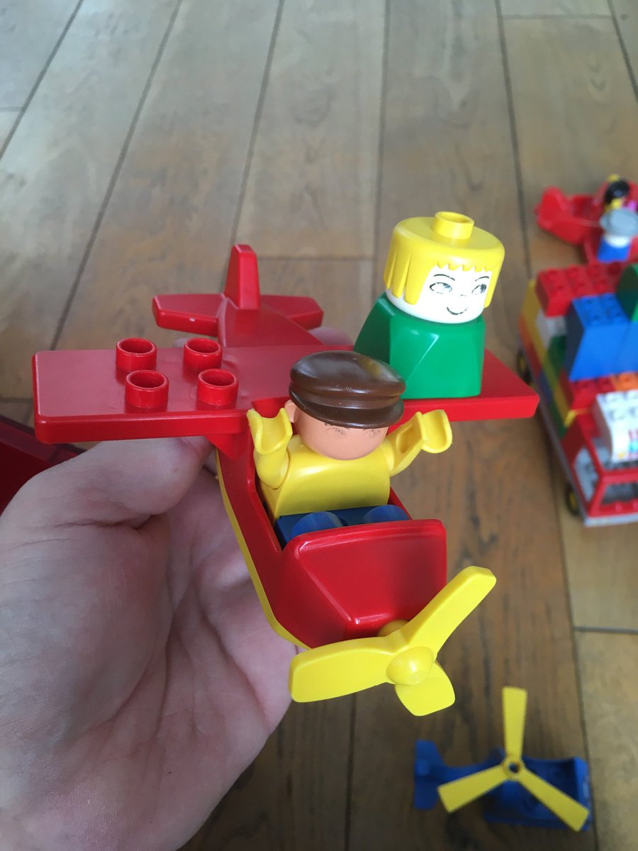 A lego plane with seats on the wings and a person sitting on them.
