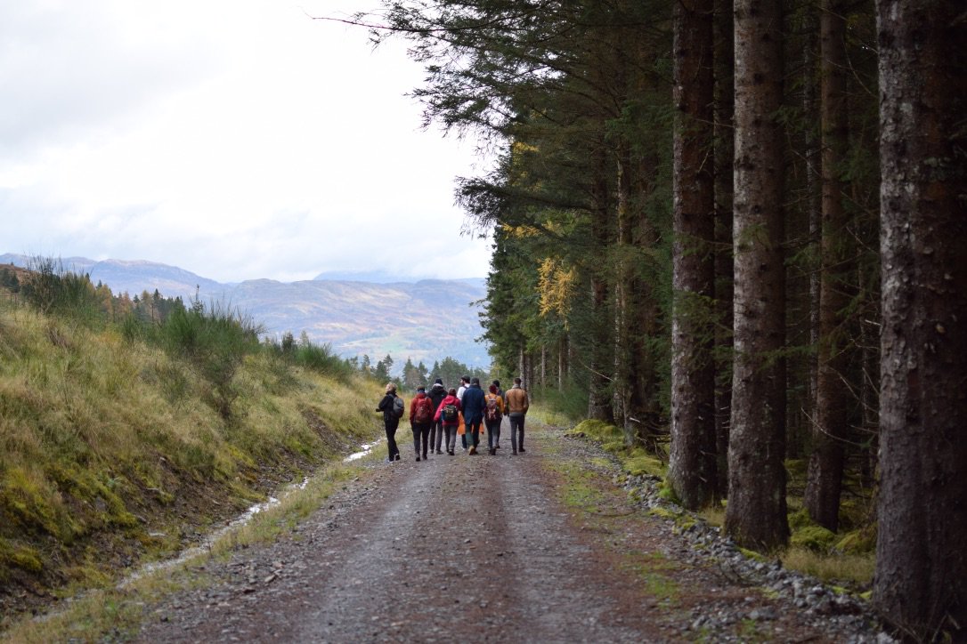 A picture of the backs of philosophy students in the distance surrounded by trees and beautiful scenery.