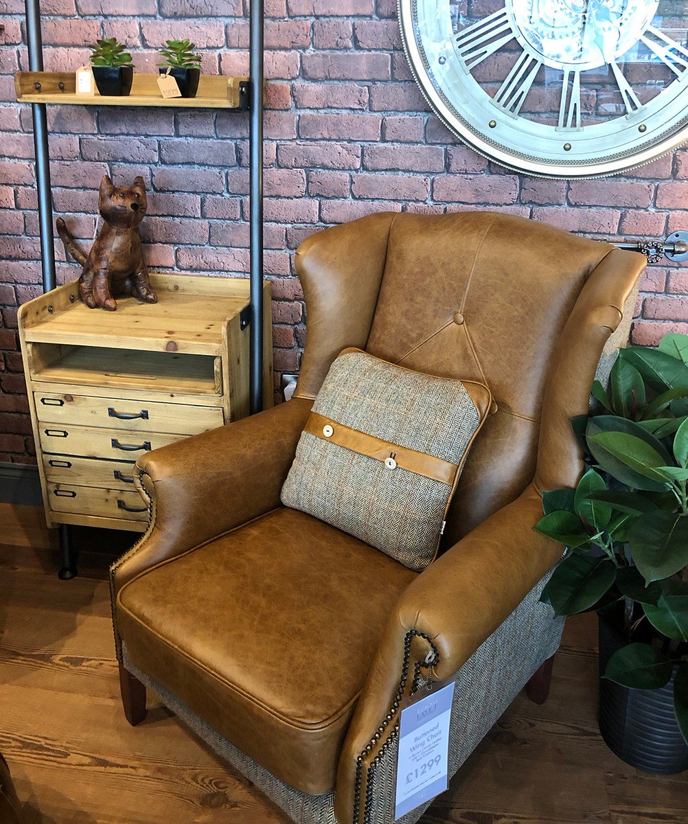 A design standout, this buttoned Brown Cerato Leather armchair with a Gamekeeper seat cushion has sloping wings, scrolled arms, buttons, studs, Harris Tweed side &amp; back panels and piped detailing.