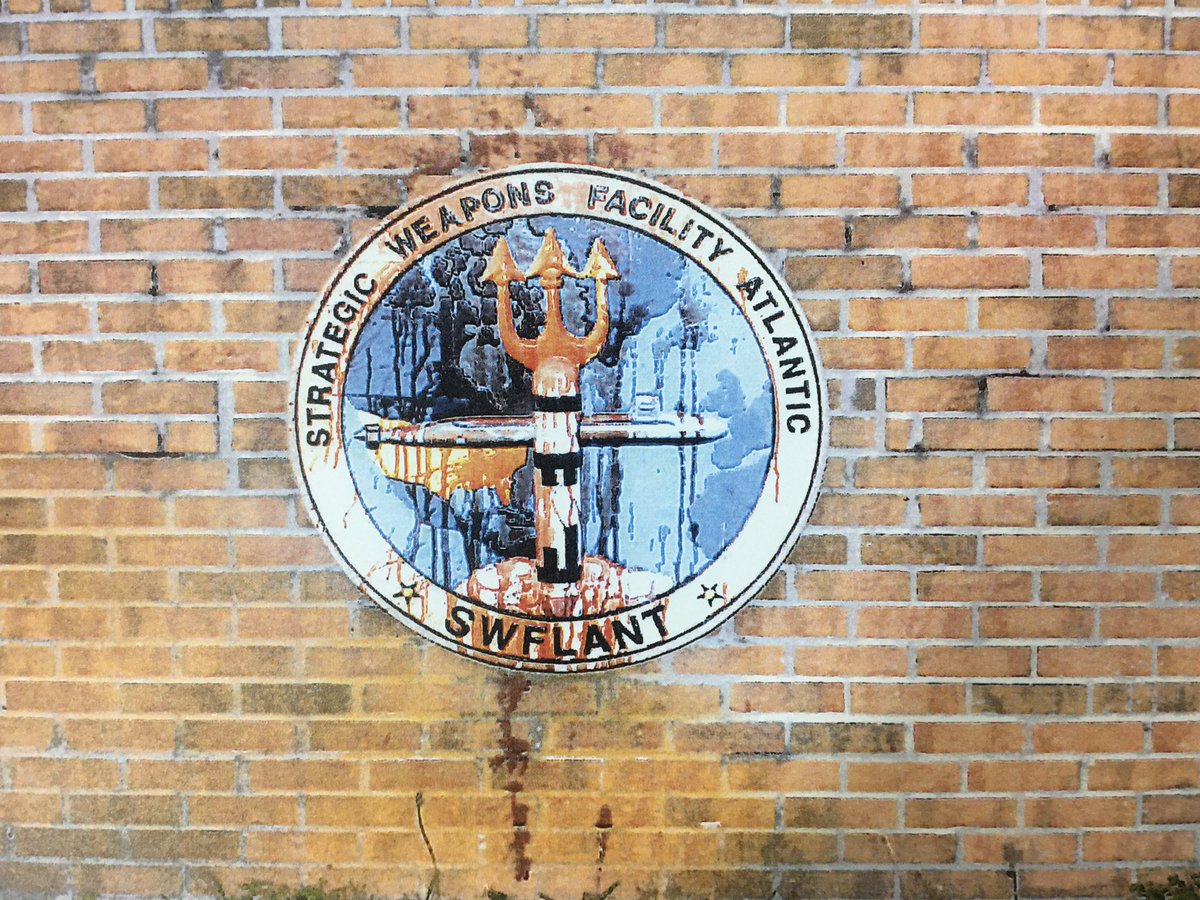 The base houses the Strategic Weapons Facility Atlantic. The activists poured human blood, the general Plowshares practice is that it’s their own, on the emblem — which depicts a submarine and a Trident missile with a pitchfork forming a cross.