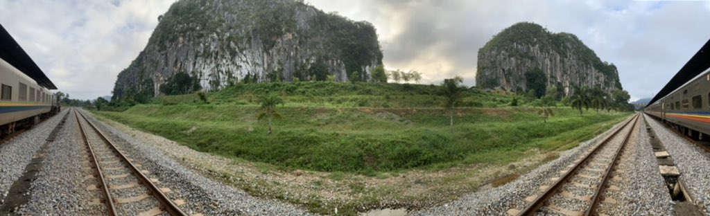 Panoramic view of train and two limestone cliffs adjacent to the station. &ndash; bei  KTM Gua Musang Railway Station (Stesen Keretapi)