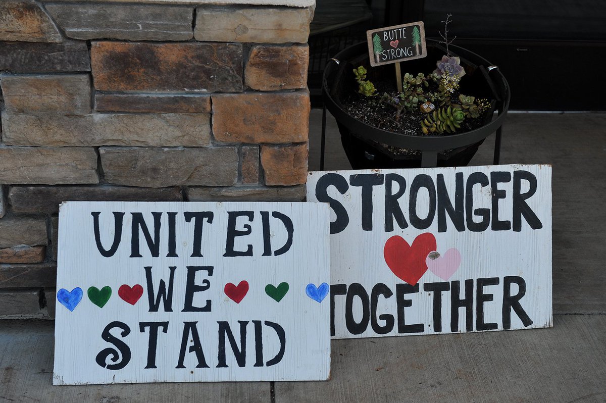 Two signs sit on the ground outside, with the messages “United We Stand” and “Stronger Together”
