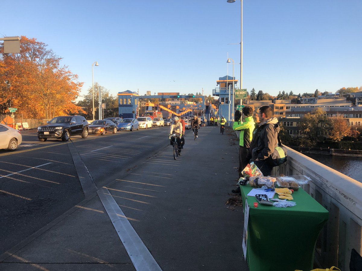 Looking north at the east side celebration table with swag on it; bike riders are riding towards the camera from the Fremont Bridge