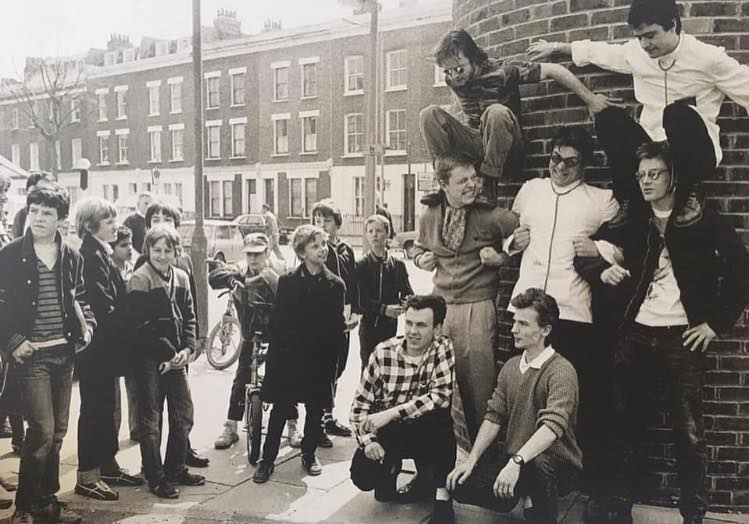 FlipLondonTours's tweet photo. Madness filming the "House Of Fun" video at the bottom of Kilburn Park Road, Shirland Road in the background, 1982. The Chemist Shop still looks the same inside, the offie was in Lauderdale Road round the corner https://t.co/x4fBUoO69O