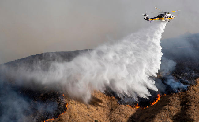 helicopter dropping water on a brush fire