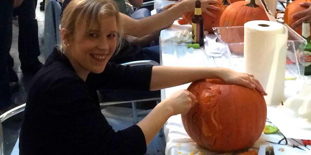 Smiling woman using a knife to carve a pumpkin