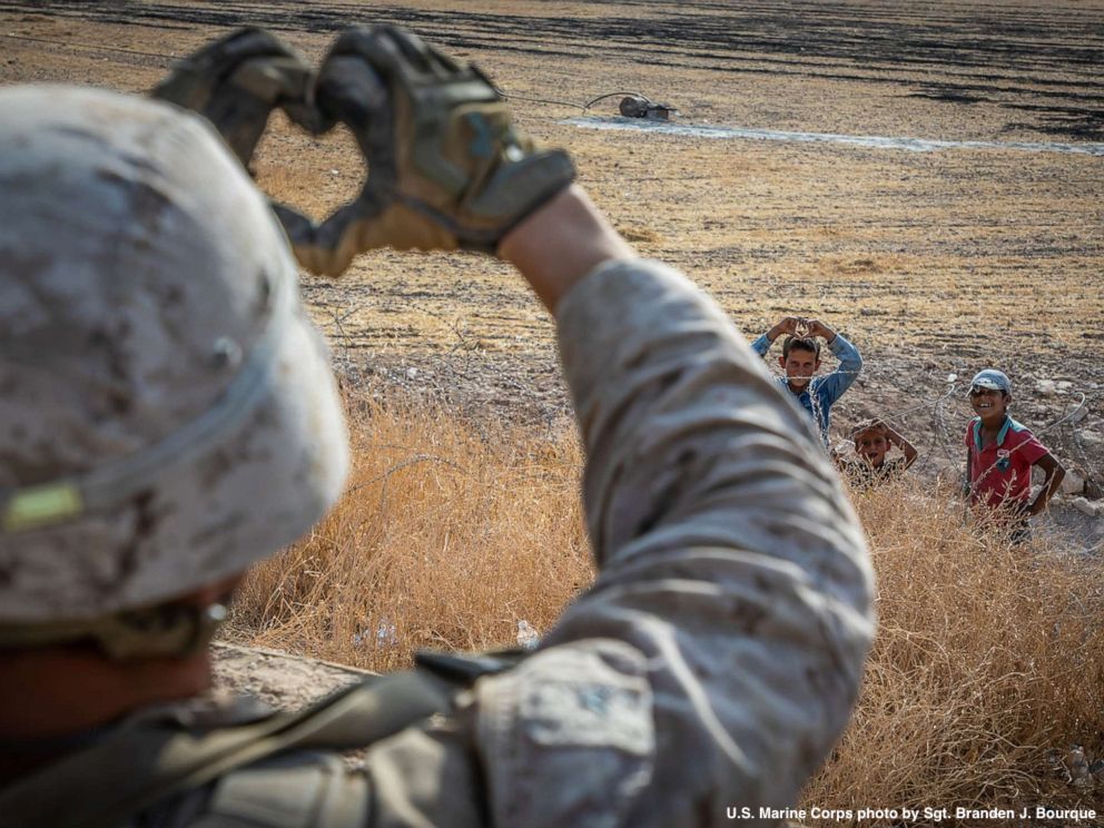 A U.S. Marine paused during his deployment in Syria to connect with three children standing nearby, a Defense Department photograph shows. abcn.ws/2C3vnmJ