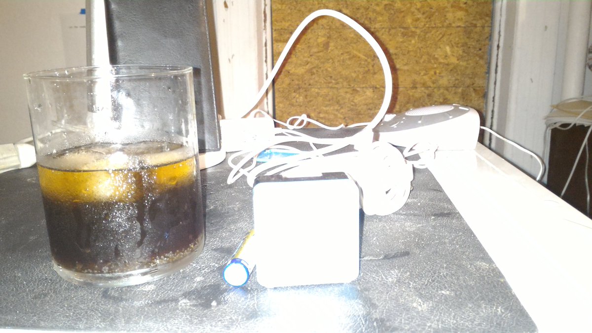 Overexposed picture of a cocktail 🍸and electronic flotsam. With boarded up window background.