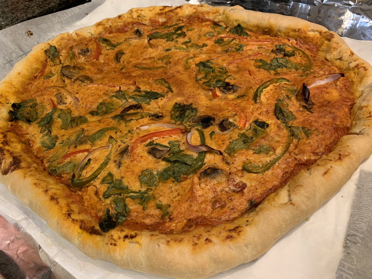 Homemade vegan pizza (pizza dough, marinara and cheese sauce) topped with red peppers, green peppers, mushrooms, spinach and red onion