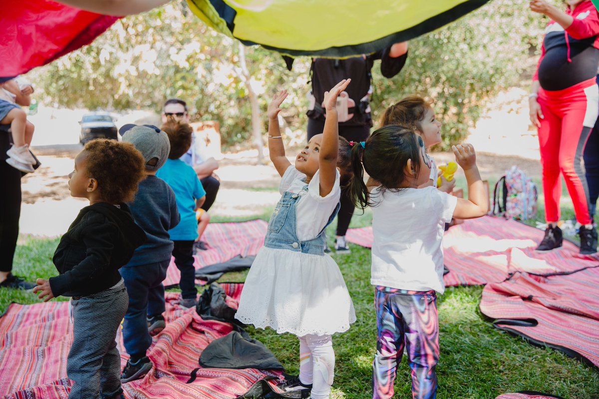 “Red and green and yellow and blue. These are the colors over you. Red for the flowers, green for the trees. Yellow for the sunshine. Blue for the seas.” So much joy and color fun under the parachute! #parachuteplay