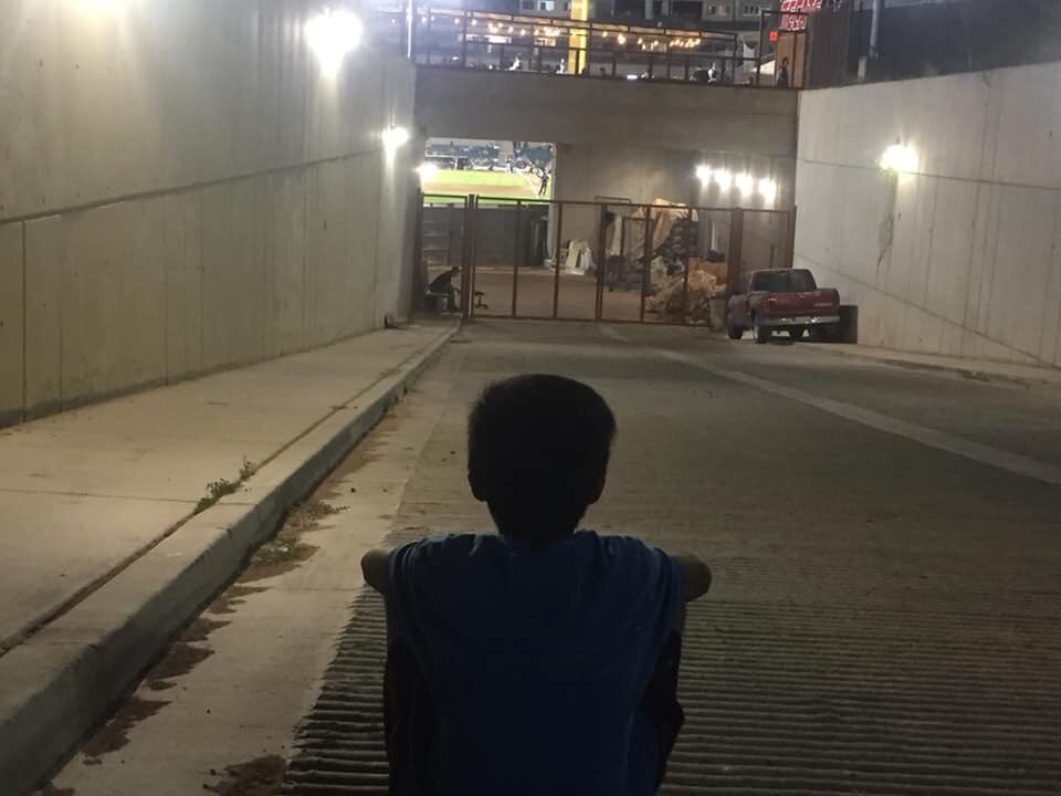 Este pequeño mira desde lejos, afuera del Estadio Sonora el Hermosillo versus Monterrey sentado en la calle.