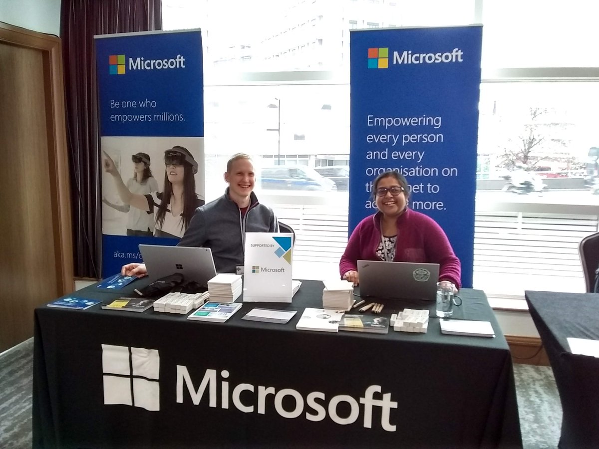 Researchers from Microsoft sit at the Microsoft table at CCS in front of two blue banners.